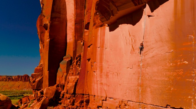 Photo courtesy of Jackson Hole Mountain Guides. Climber scaling a crack in brilliant red sandstone.
